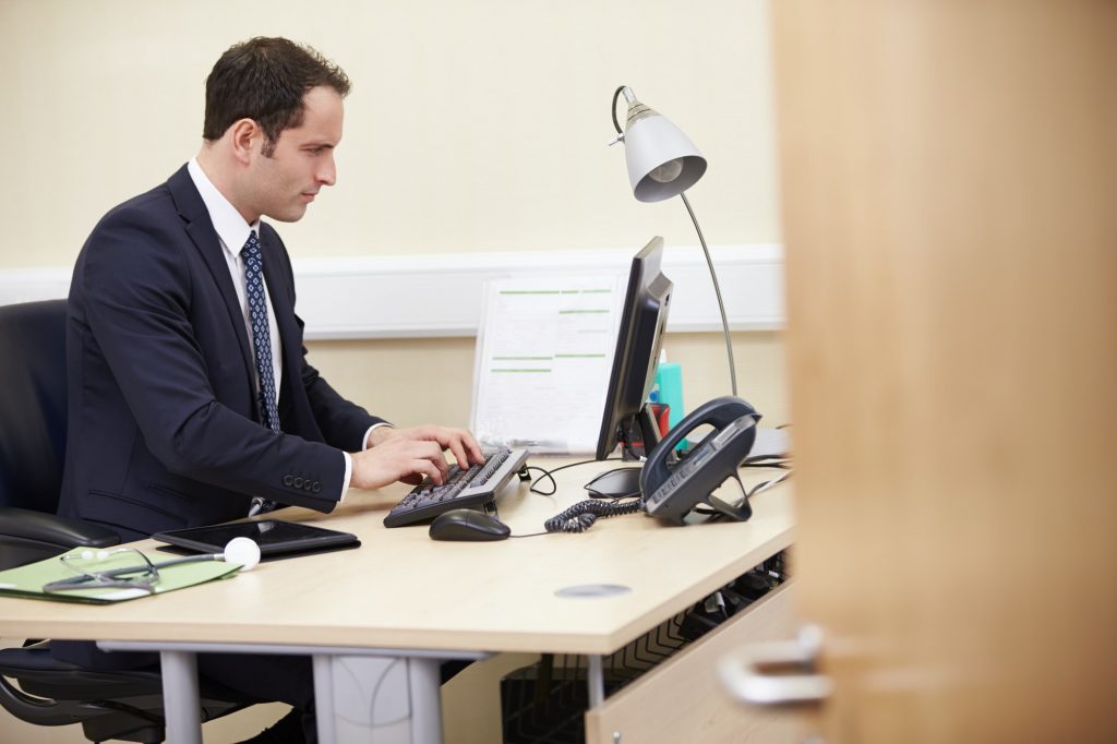 Male Consultant Working At Desk In Office